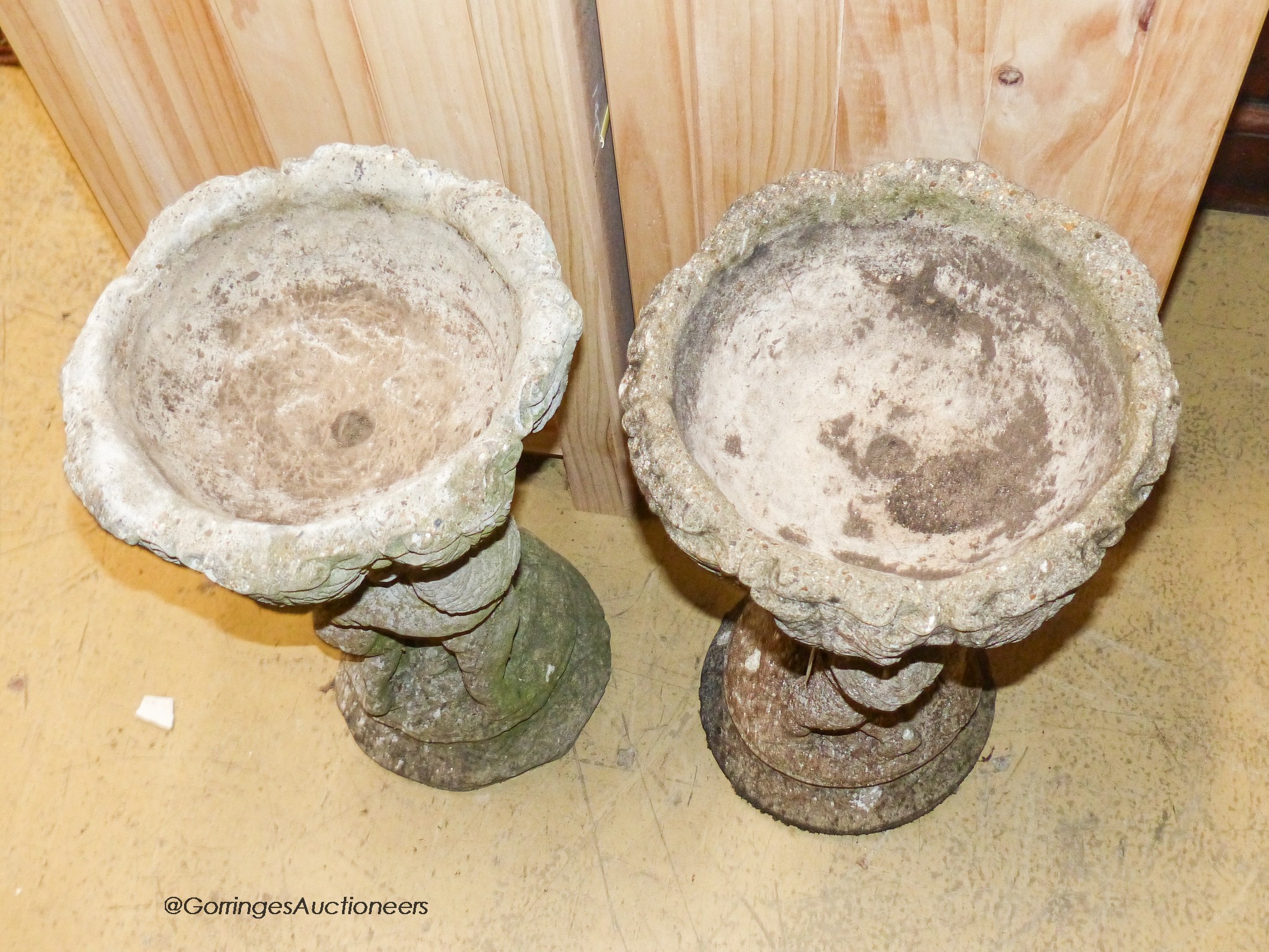 A pair of reconstituted stone circular tulip form planters on figural cherub plinths, diameter 29cm, height 55cm